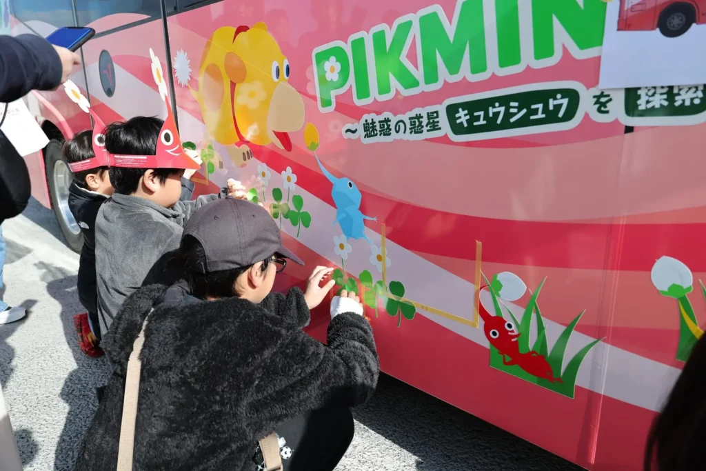 Children decorating a bus with Pikmin decals