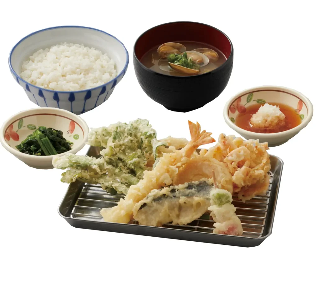 A series of small plates and bowls holding tempura, spinach, rice, soup and grated radish