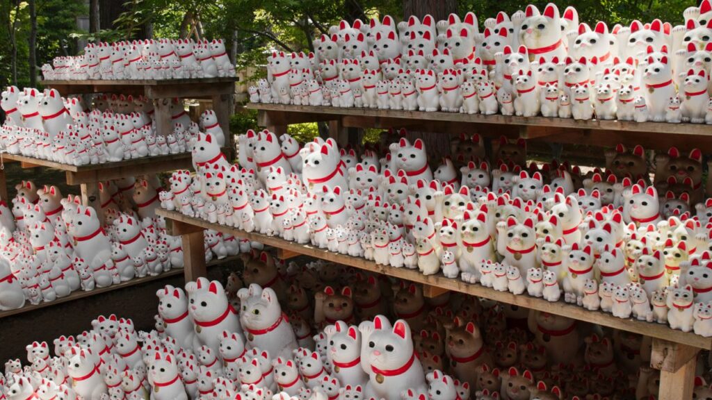 A large number of Maneki Neko cat statues on a series of shelves