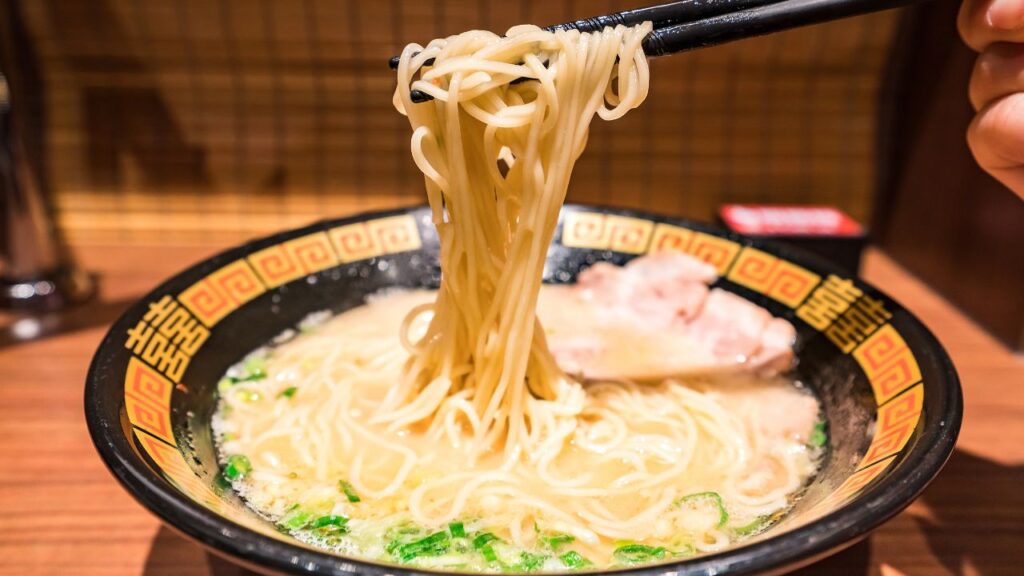 Ramen being lifted out of a bowl by a pair of chopsticks