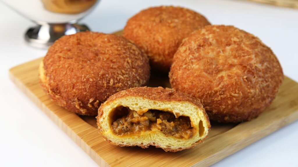 A wooden plate holding four pieces of curry bread