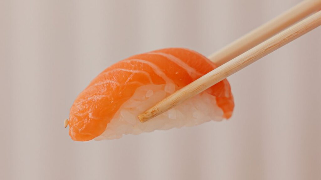 Salmon sushi being picked up by a chopstick