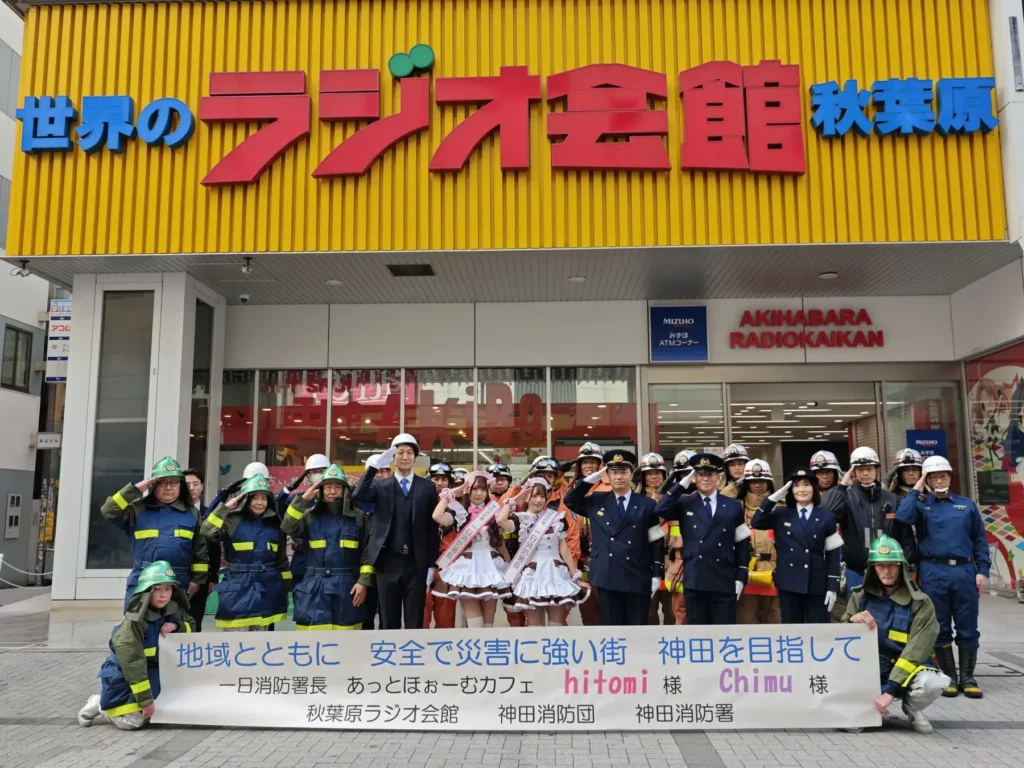 A group of fire fighters and maids standing outside the Radio Kaikan building