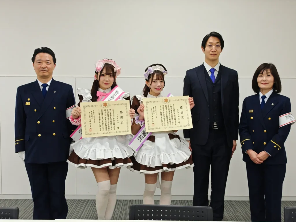 Two maids being awarded certificates by fire fighters