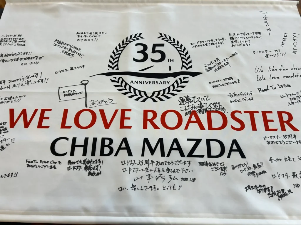 A flag that reads "WE LOVE ROADSTER, CHIBA MAZDA" and signed by multiple people