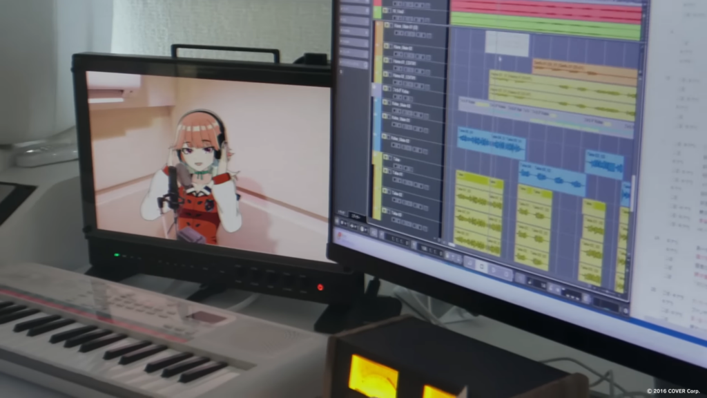 Two monitors on a desk. One showing audio software and the other showing a virtual character singing.